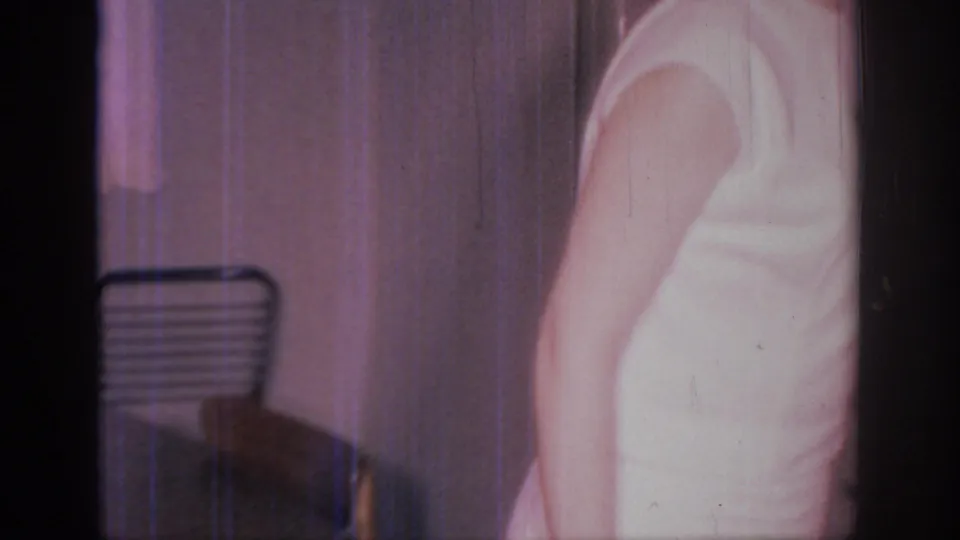 A woman in a sleeveless white dress is partially framed as she moves through a private Sacramento home interior in 1966 footage.