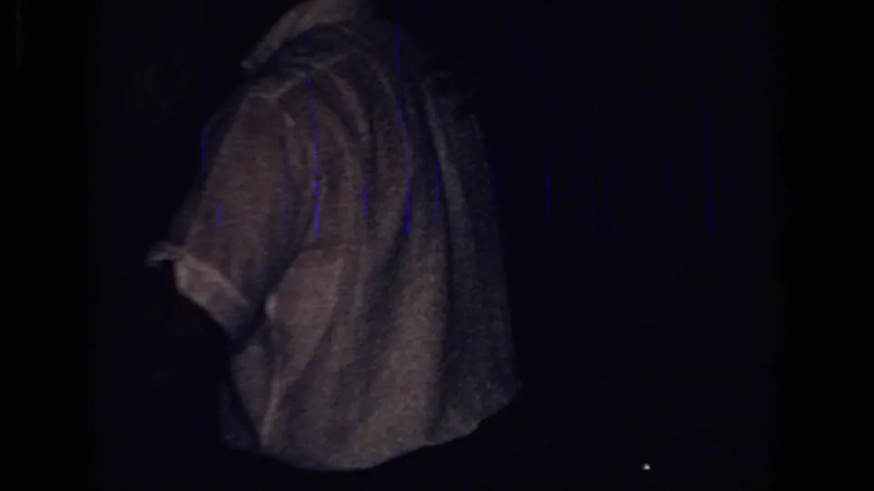 Low-light 1966 Sacramento home-movie frame with a white-shirted person turned away and little surrounding detail visible.