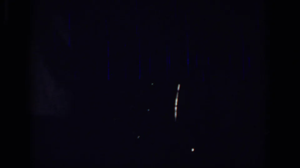 Final low-light Sacramento 1966 frame with the white-shirted figure barely visible amid grain, streaking, and scattered light points.