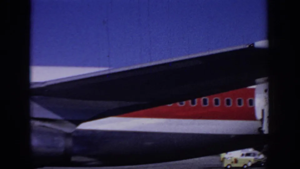 1966 Sacramento frame showing the rear area of a TWA jet, with wing structure, red fuselage stripe, and a small vehicle below.