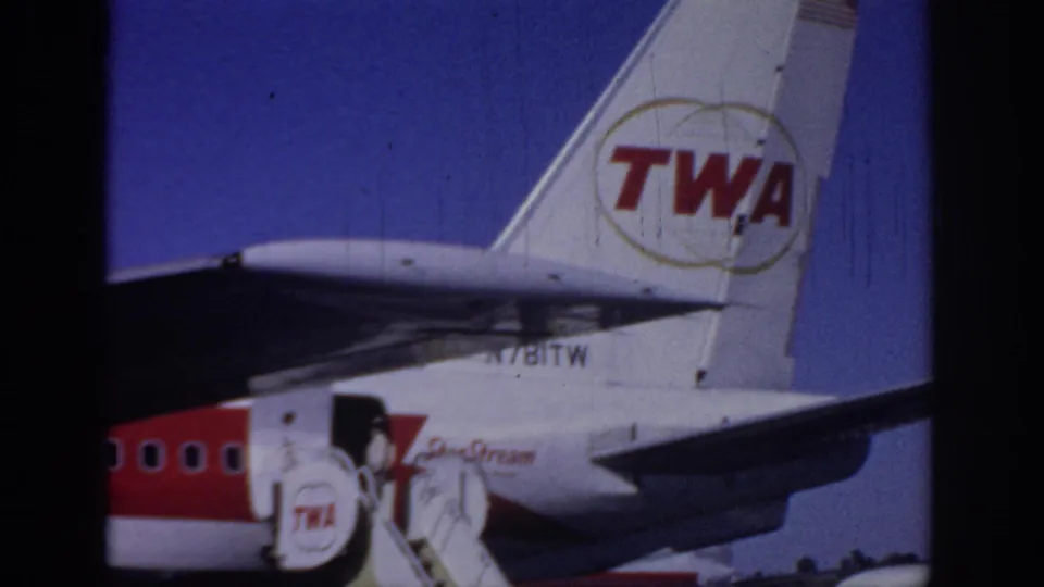 1966 Sacramento frame with the TWA tail logo, rear fuselage, wing area, and mobile stairs beside the aircraft door.