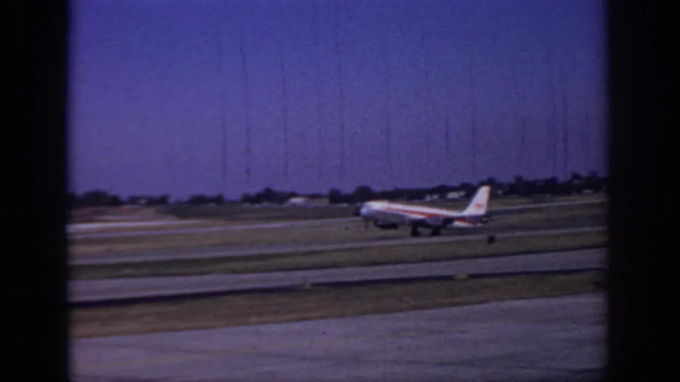 Side view of a 1966 Sacramento runway scene with a commercial jet, grass strips, distant airport structures, and pronounced film scratches.
