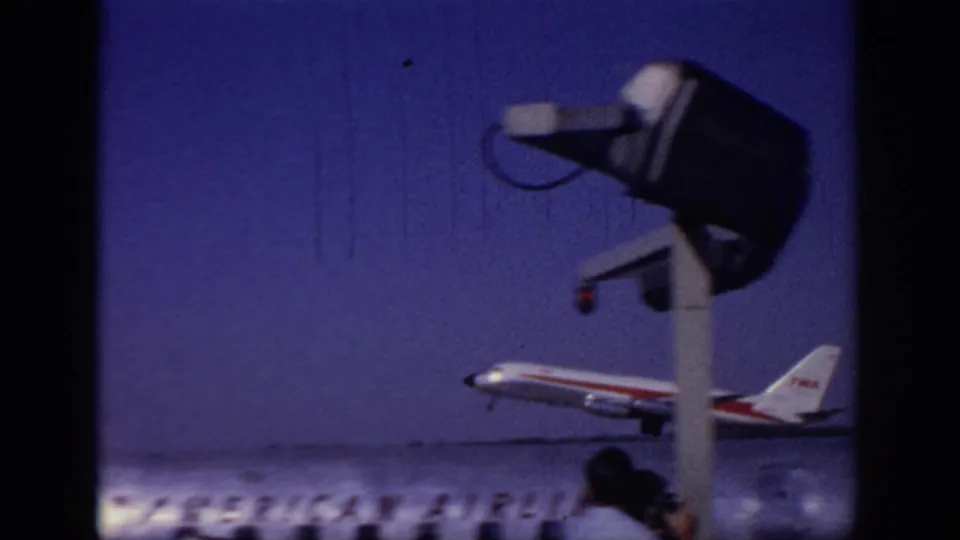 1966 Sacramento airport frame of a TWA jet beginning takeoff, with airport equipment and small spectators visible near the runway area.