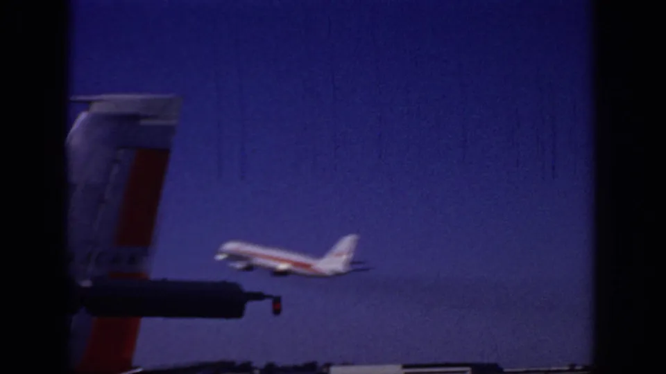 1966 Sacramento home-movie frame showing a passenger jet taking off against a deep blue sky, with a partial aircraft tail in the foreground.