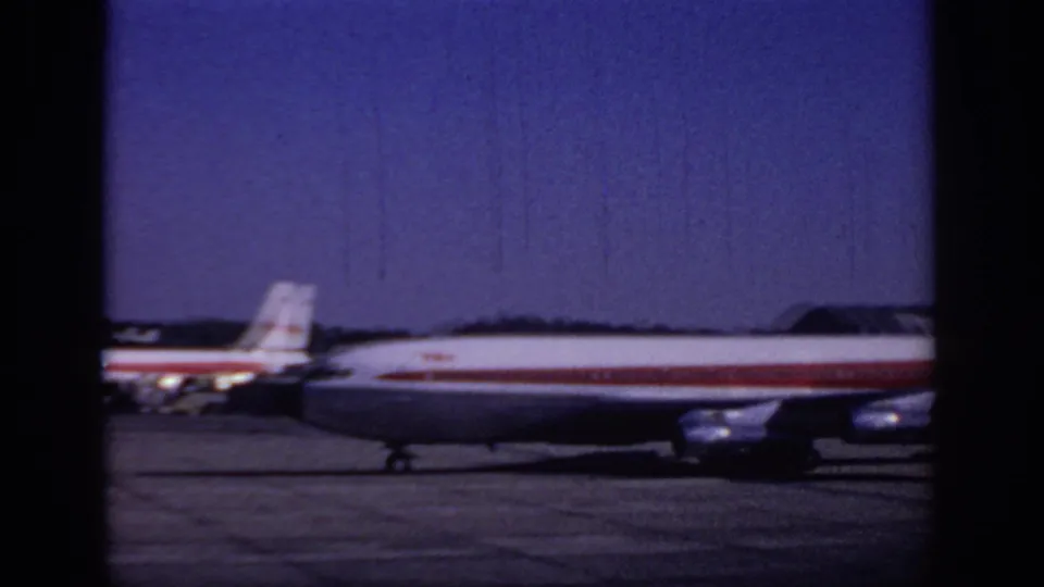The airliner passes close to the camera position, filling the lower frame with fuselage, tail, landing gear, and red stripe detail.
