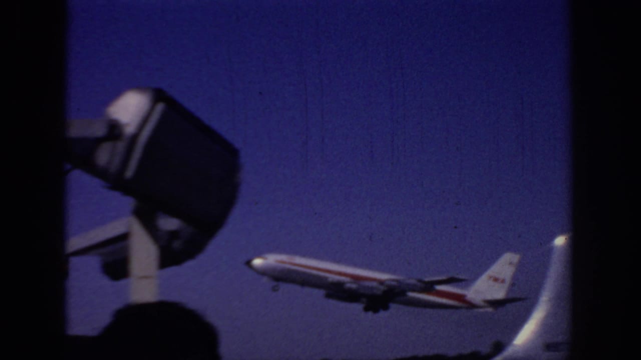 1966 Sacramento airport footage showing a TWA passenger plane climbing against a deep blue sky from a low home-movie angle.