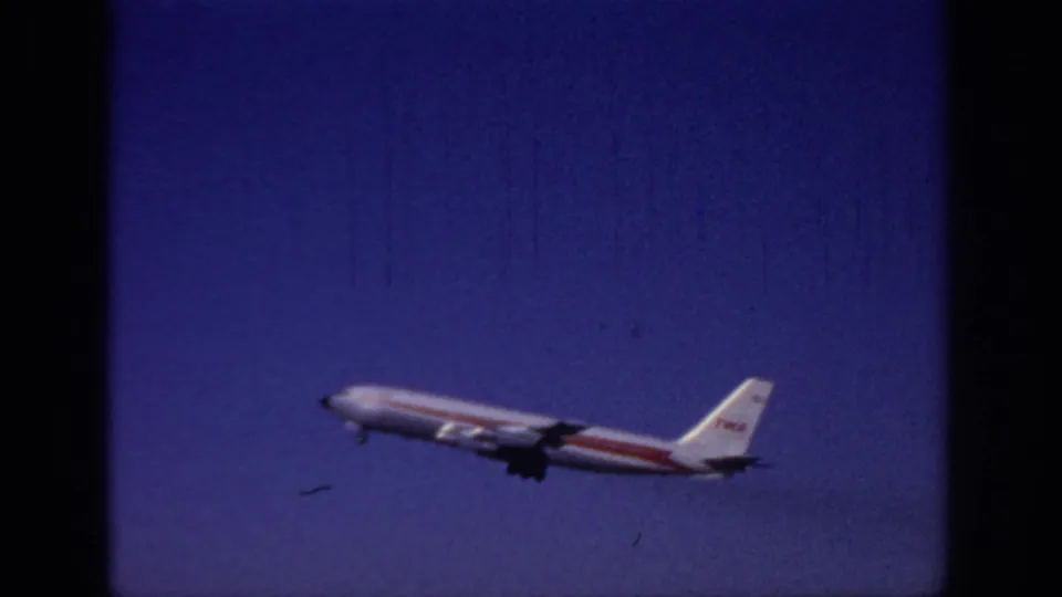 TWA passenger plane in white and red livery climbs through the Sacramento sky in 1966 home-movie footage.