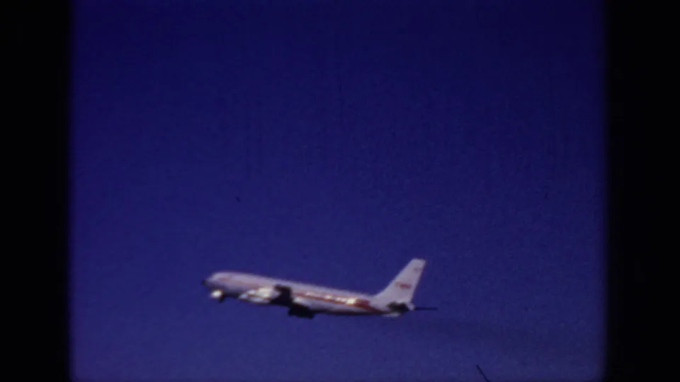 The TWA plane appears smaller as it continues its takeoff climb across the blue sky over Sacramento in 1966.