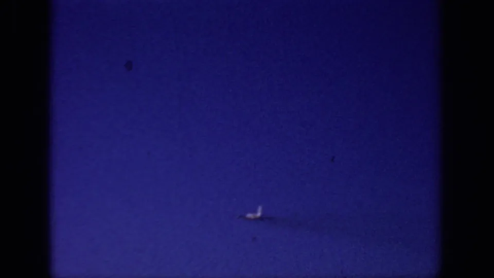 Final visible frame shows the small aircraft low against the blue Sacramento sky, with a faint trailing mark and aged 8mm color grain.