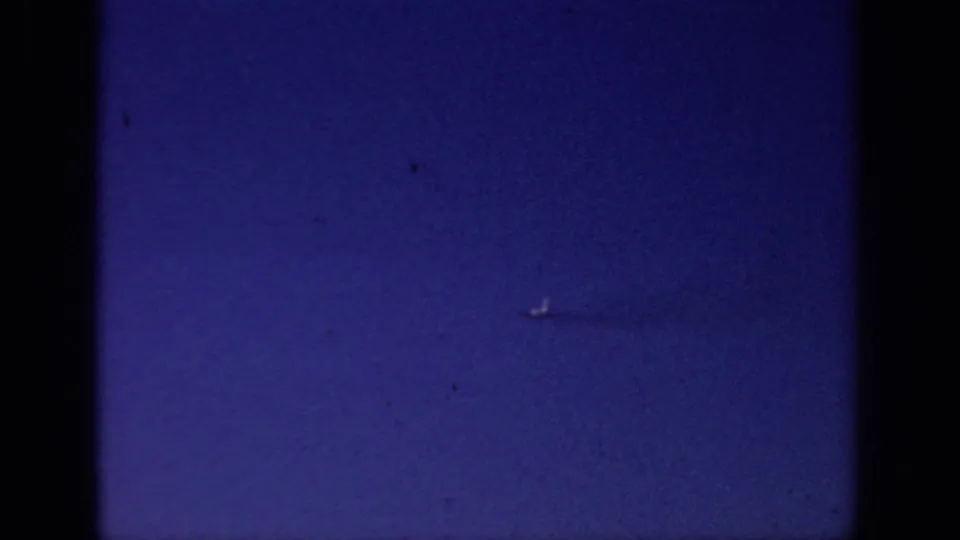 Distant flying object in a blue 1966 Sacramento sky frame, with visible film grain, dust, and vignetted 8mm edges.