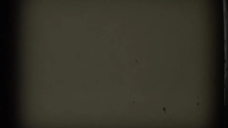 End frame from the 8mm clip showing little visible subject detail, with muted exposure, grain, dust, and a dark frame edge.