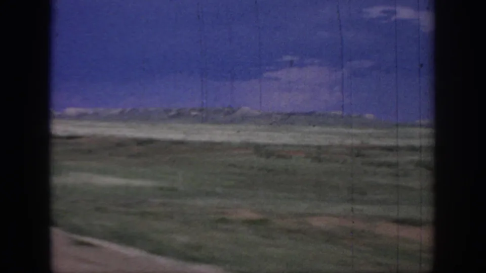1967 Oklahoma road-trip view of open plains, low horizon, blue sky, and dark window framing from a moving vehicle.