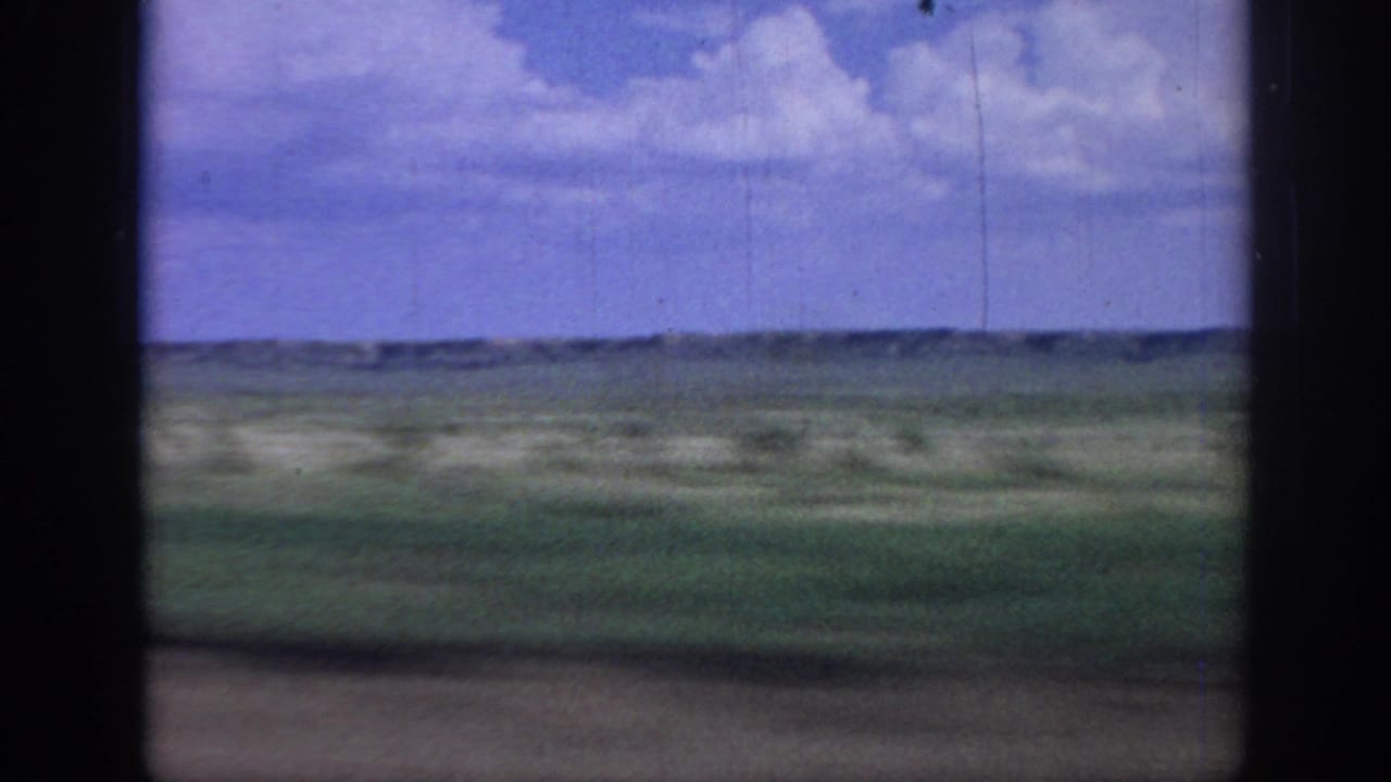 Passenger-side view of rural Oklahoma fields in 1967, softened by motion blur and aged 8mm color.