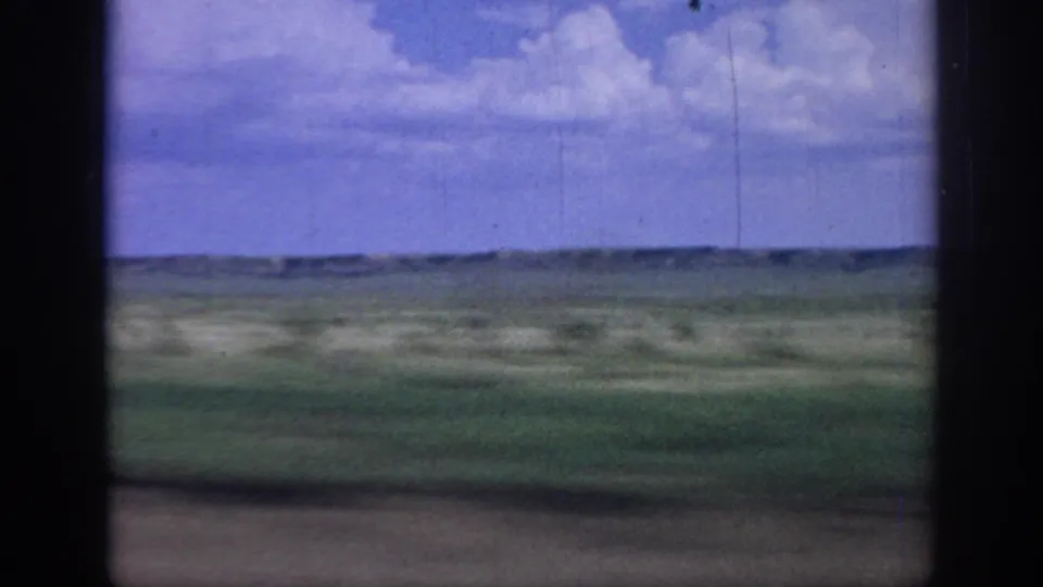 Passenger-side view of rural Oklahoma fields in 1967, softened by motion blur and aged 8mm color.