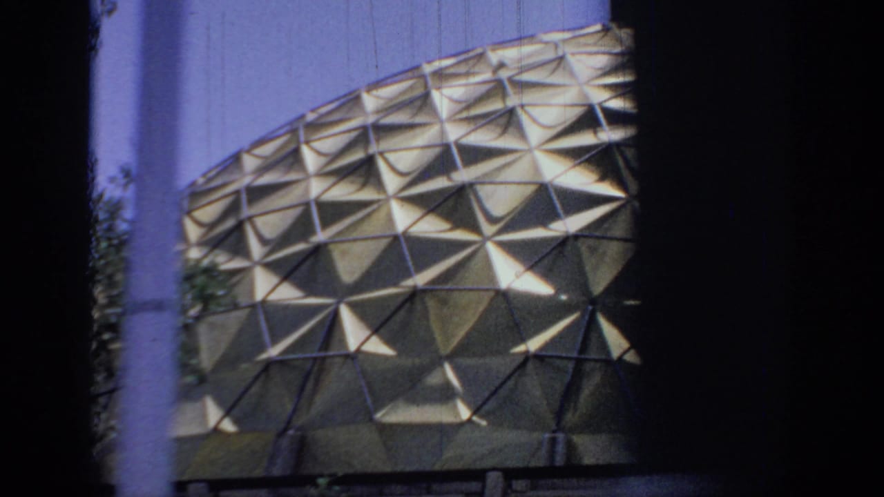 1967 Oklahoma 8mm frame showing a triangular-patterned dome facade seen through dark roadside or vehicle framing.