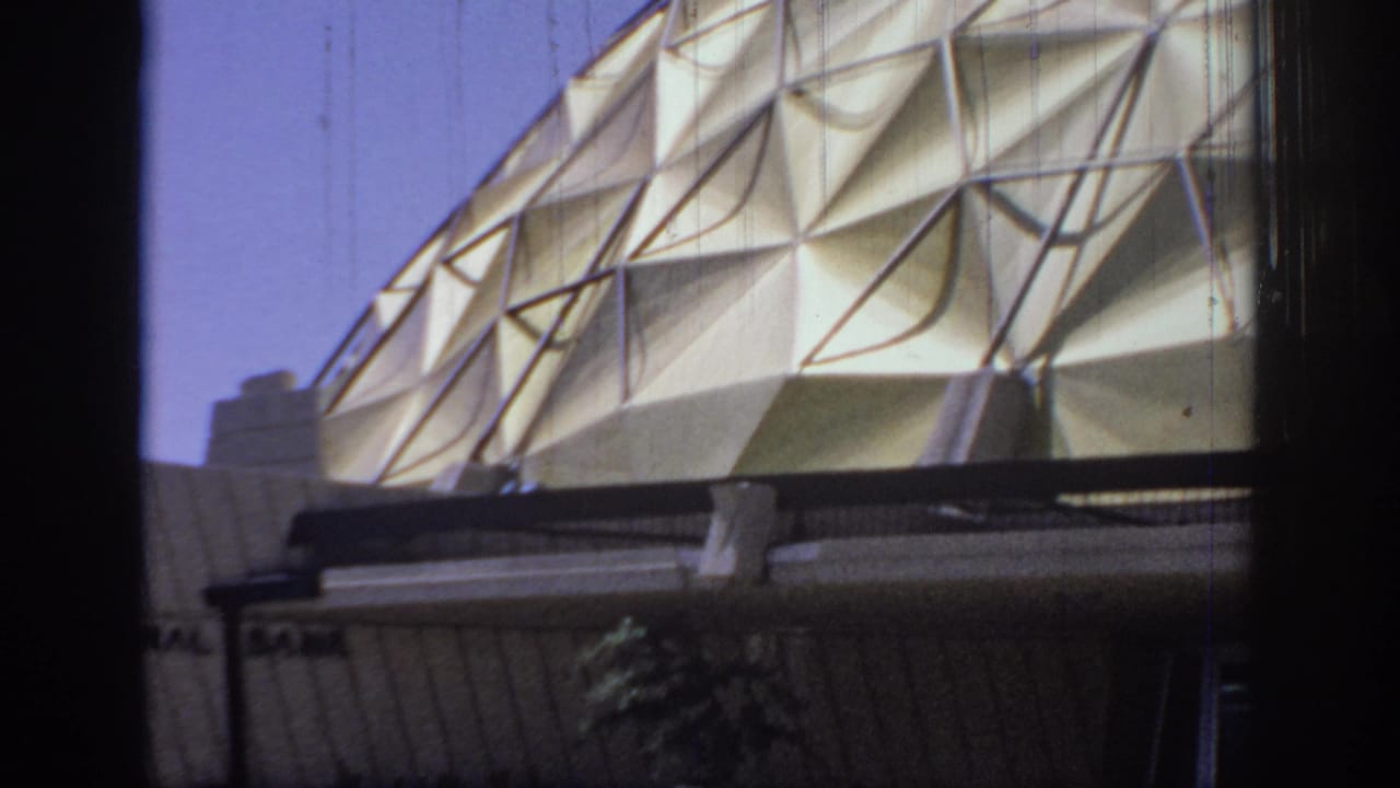1967 Oklahoma 8mm frame showing a cream geodesic dome with triangular patterned panels and partial roofline below.