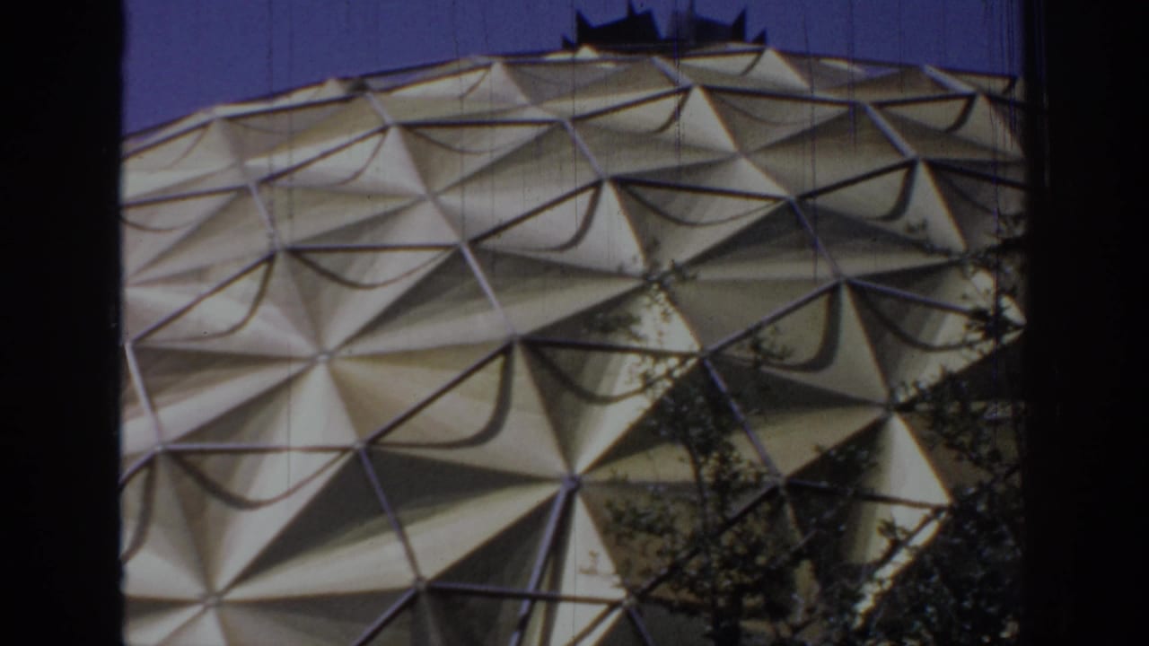 Final 8mm frame showing the Oklahoma dome's triangular exterior with nearby tree foliage along the lower edge.