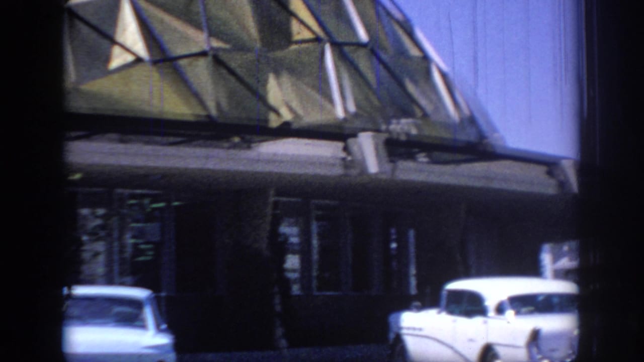 Oklahoma 1967 home-movie frame showing the dome base, shaded entrance, and white period automobiles parked nearby.