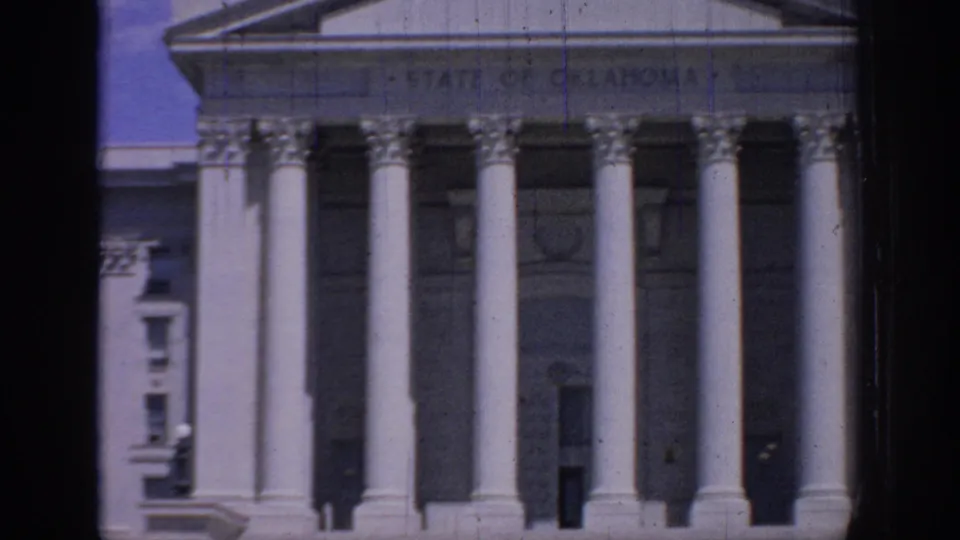 Oklahoma State Capitol entrance in 1967 8mm footage, showing the State of Oklahoma inscription above tall columns.