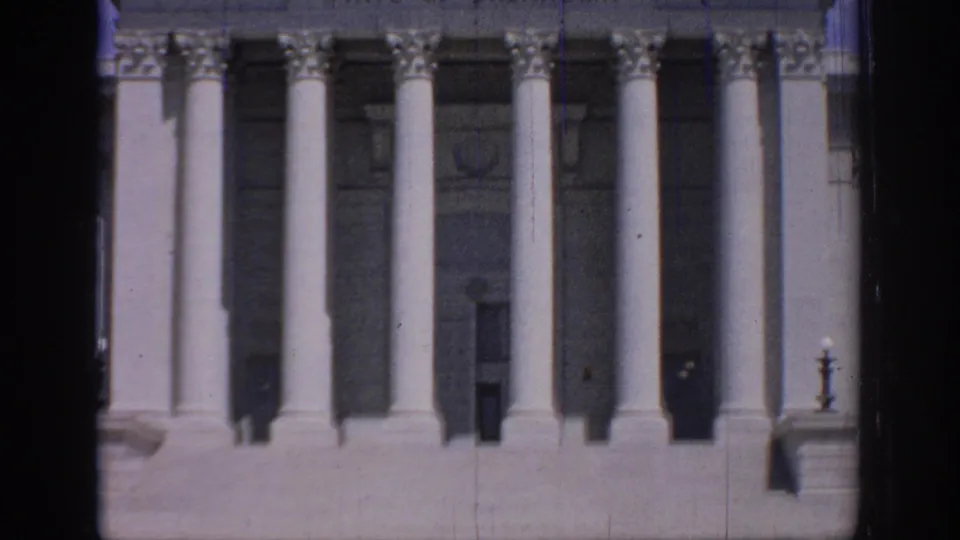 Close exterior view of the Oklahoma State Capitol entrance in 1967 home-movie footage, with tall columns and dark recessed doorways.