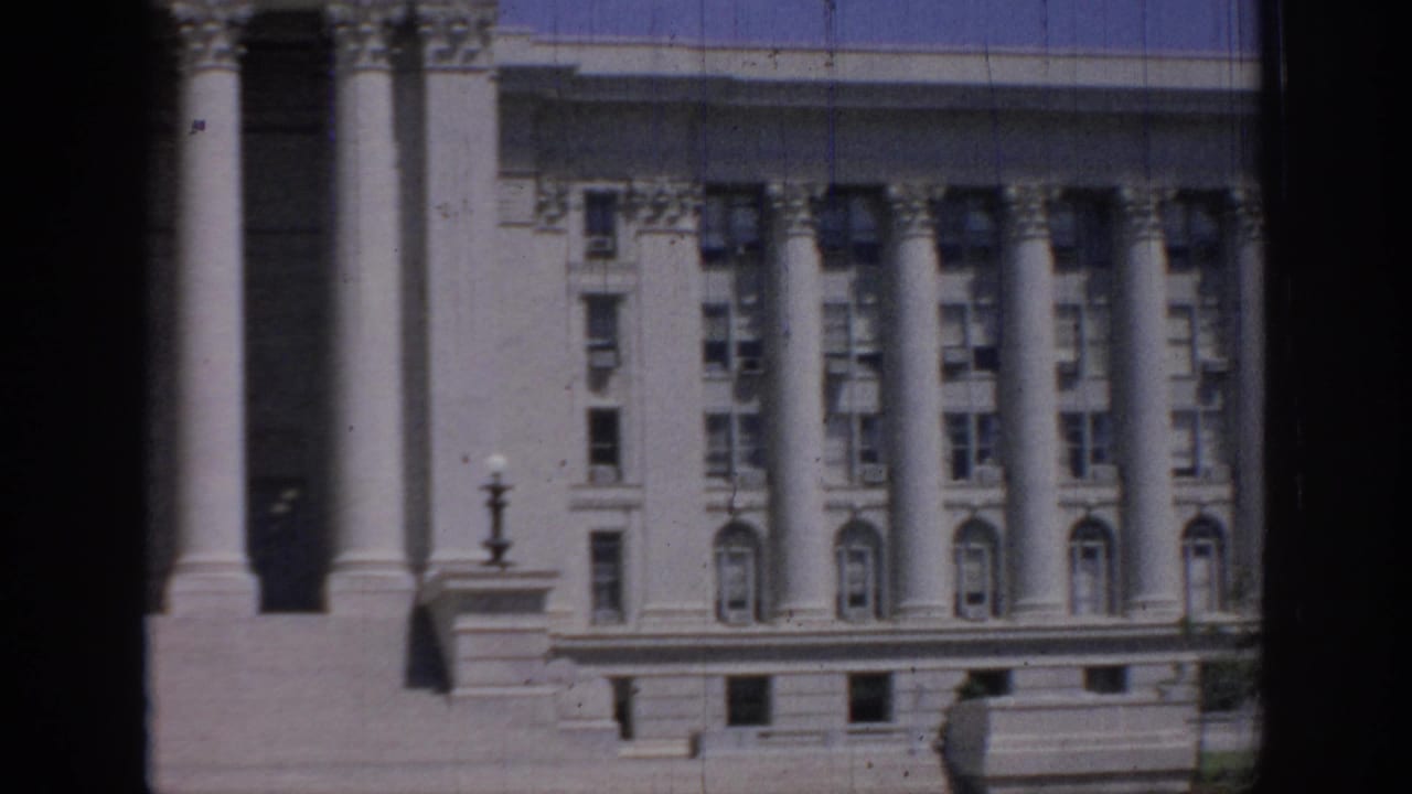 1967 Oklahoma 8mm frame showing a classical multi-story building with tall columns, arched windows, and dark foreground framing.