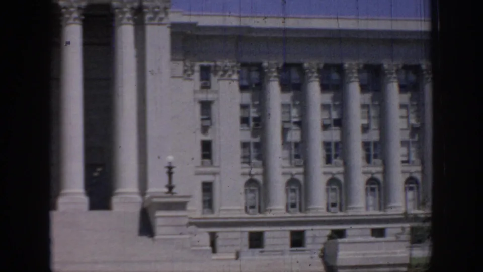 1967 Oklahoma 8mm frame showing a classical multi-story building with tall columns, arched windows, and dark foreground framing.