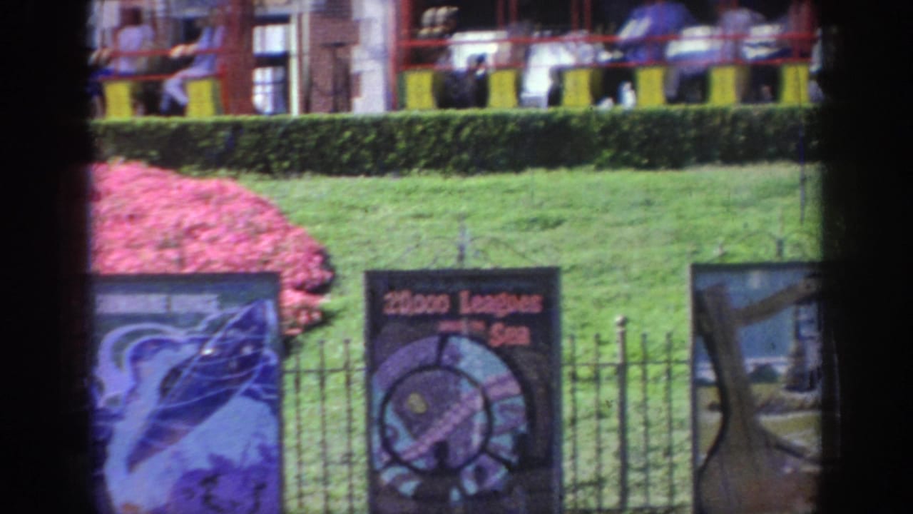 A public attraction area in Oklahoma shows lawns, fencing, illustrated signs, and a small passenger train in the background.