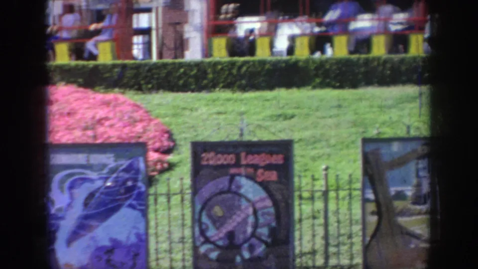 A public attraction area in Oklahoma shows lawns, fencing, illustrated signs, and a small passenger train in the background.