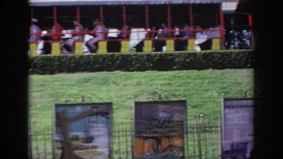 A small passenger train carries visitors past fenced lawns and display signs in 1967 Oklahoma home-movie footage.