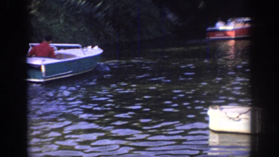 1967 Oklahoma river frame showing the main motorboat in the foreground and a second boat farther away on dark water.