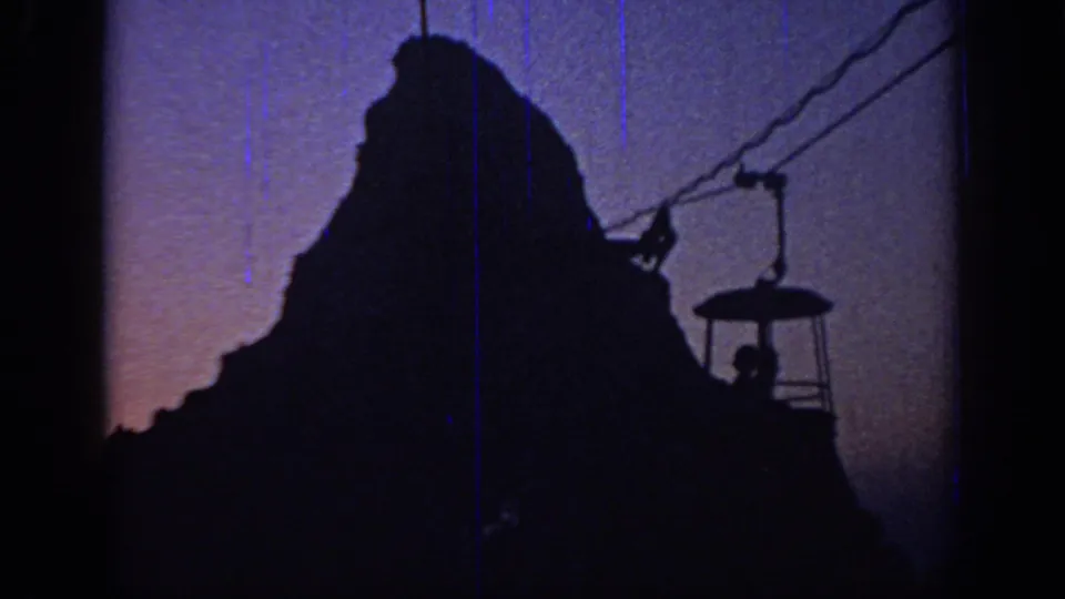 1967 Oklahoma home-movie view of a cable car passing beside a dark mountain-shaped amusement-park feature.