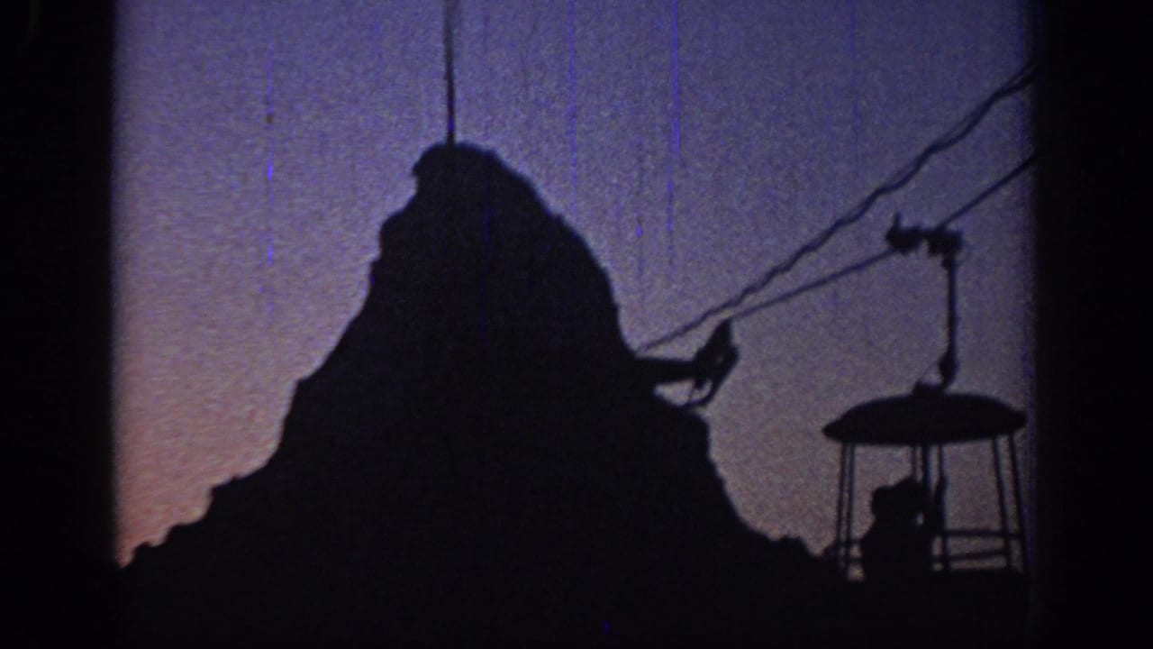 1967 Oklahoma 8mm frame showing a silhouetted cable car and cables against a purple dusk sky.