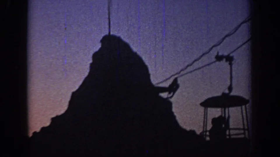 1967 Oklahoma 8mm frame showing a silhouetted cable car and cables against a purple dusk sky.