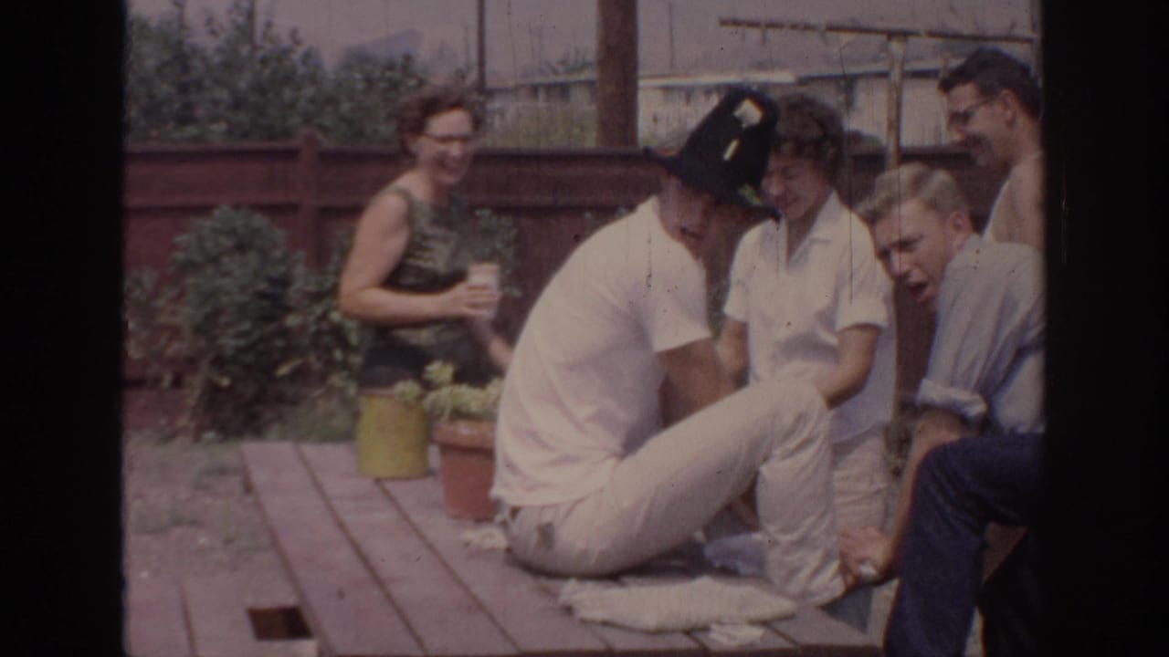 1967 Oklahoma backyard gathering with adults seated and standing around a wooden picnic table during a casual party.