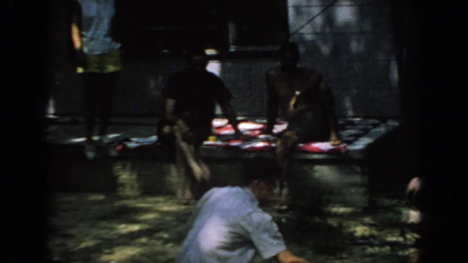 1967 Oklahoma park scene with people seated by picnic plates while the barbecue continues at the edge of the frame.