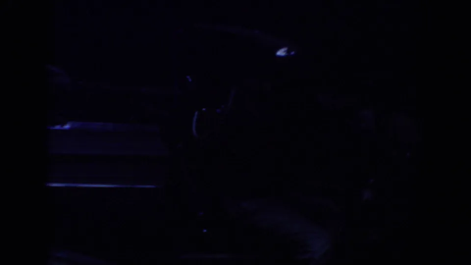 End frame shifts into deep shadow, with the outline of a parked car faintly visible in the 8mm exposure.