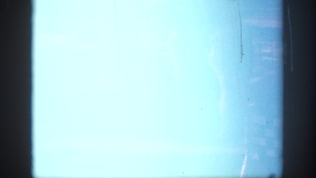 A mostly overexposed 8mm frame with a pale blue field and only a small visible portion of the Oklahoma park picnic at the upper right.