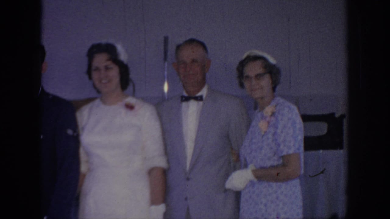 1967 Oklahoma wedding footage shows a bride beside an older man in a gray suit and an older woman in a patterned blue dress.