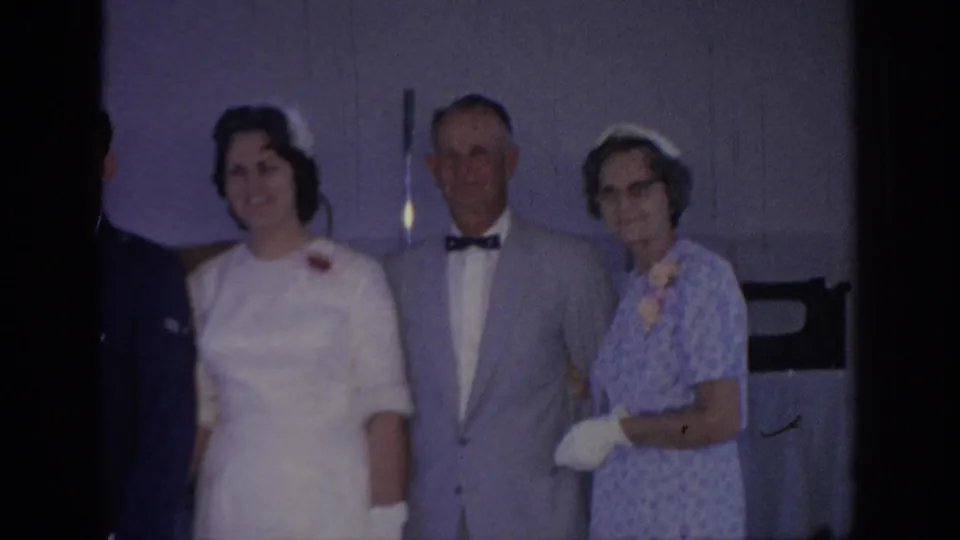 1967 Oklahoma wedding footage shows a bride beside an older man in a gray suit and an older woman in a patterned blue dress.