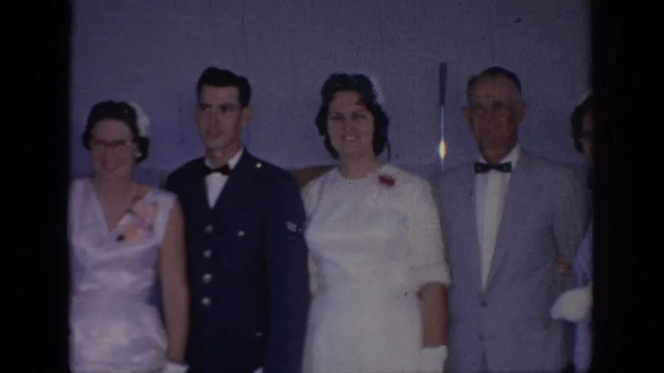 1967 Oklahoma wedding footage shows the bride with a uniformed man and older relatives in a dim indoor portrait setup.