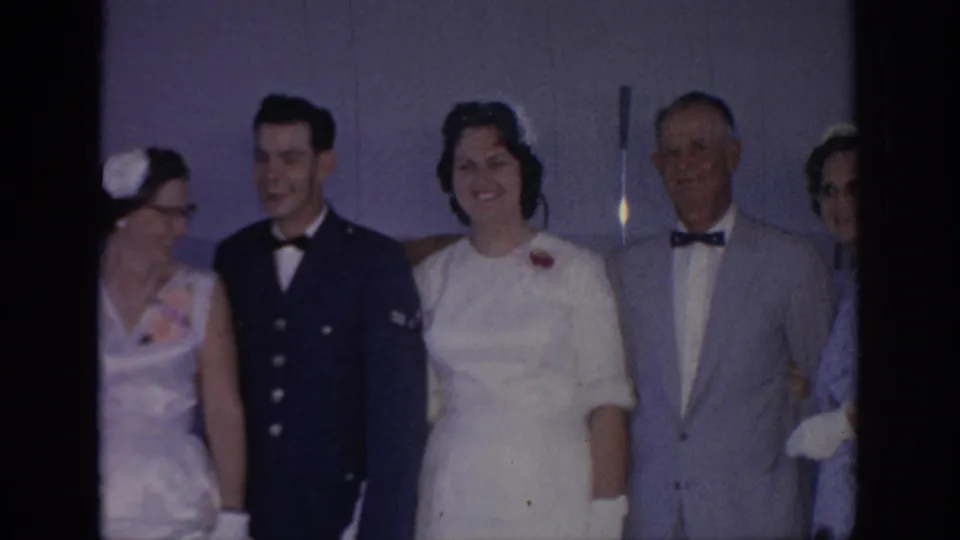 A 1967 Oklahoma wedding group smiles and turns slightly as the home-movie camera records the indoor family portrait.