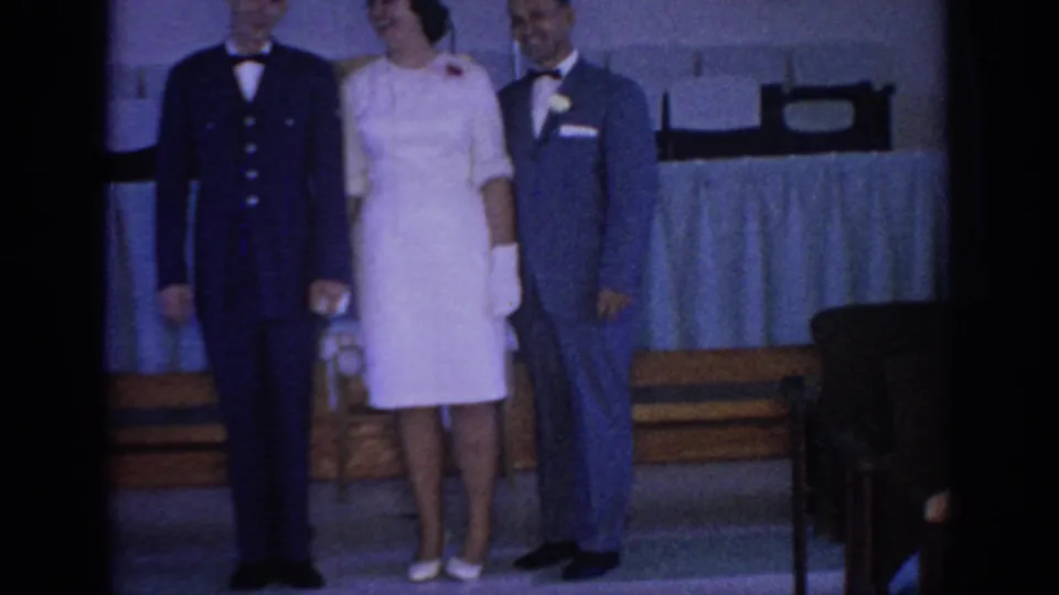 The wedding party stands together in a 1967 Oklahoma interior, with the bride between a uniformed man and groom in blue.