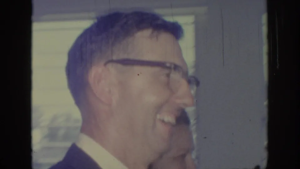 A smiling man with glasses is shown in profile in the 1967 Oklahoma home-movie wedding footage.