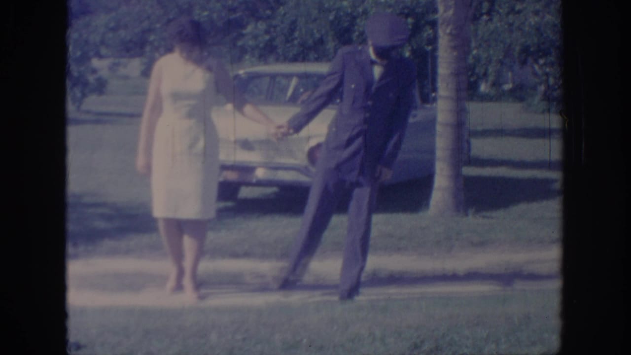 The uniformed man and woman in a white dress appear to dance or playfully step apart on an Oklahoma lawn in 1967 footage.