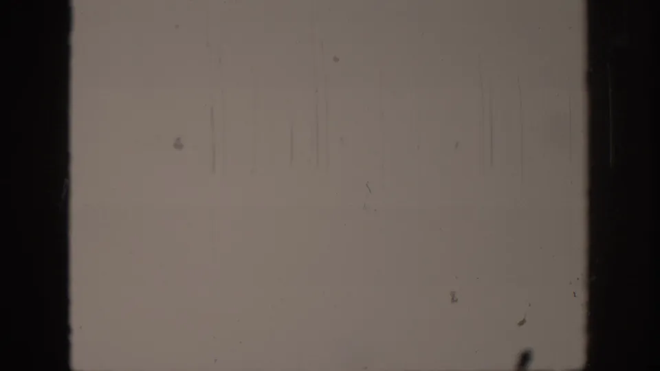 A final mostly blank 8mm frame shows vertical scratch lines, dust, and dark film edges.