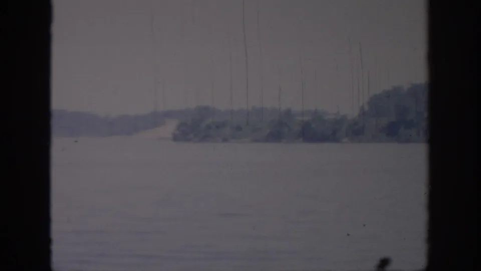 1967 Oklahoma 8mm frame showing open water, a distant wooded shore, pale sky, and dark foreground framing.