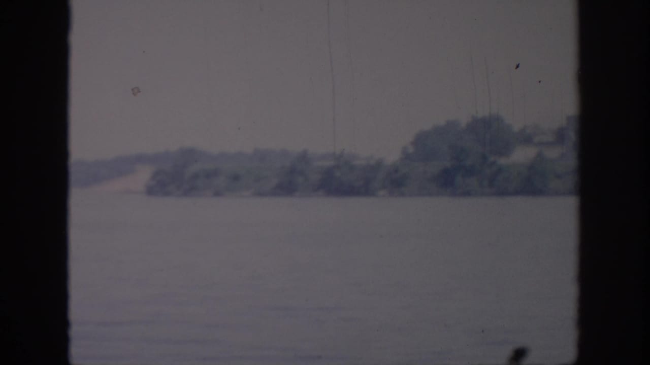 1967 Oklahoma 8mm view of a wooded shore across a broad body of water, softly focused and faded.