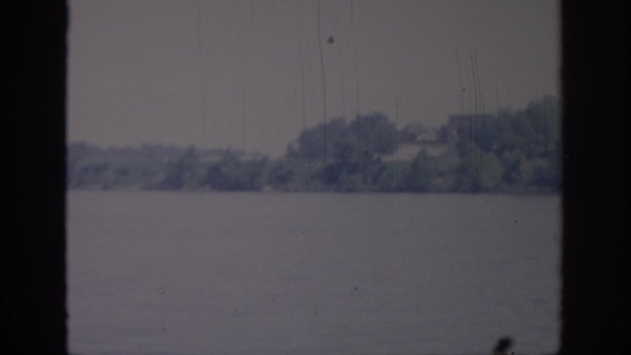 1967 Oklahoma 8mm frame with open water in front of a soft distant treeline and indistinct shore details.