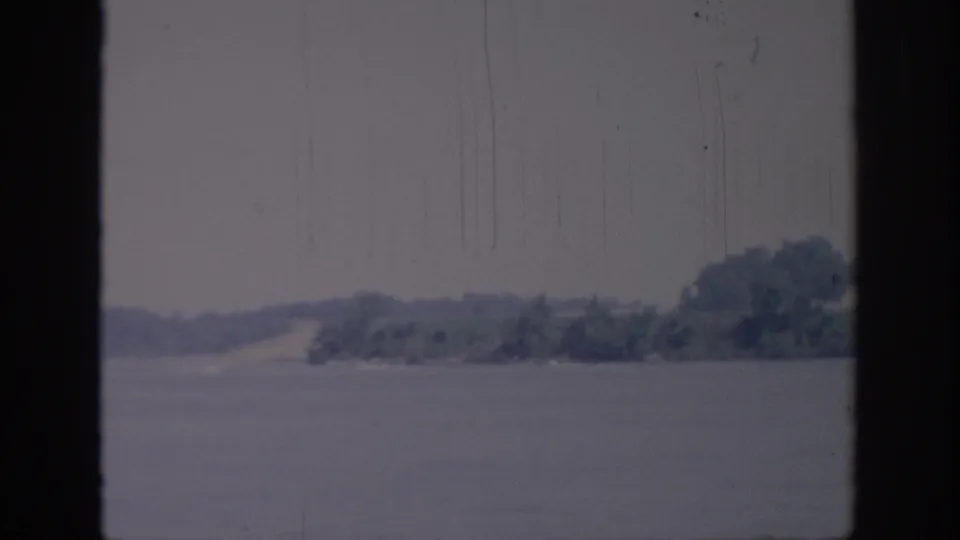 Steady 1967 Oklahoma home-movie view across water toward a soft, tree-lined shoreline.
