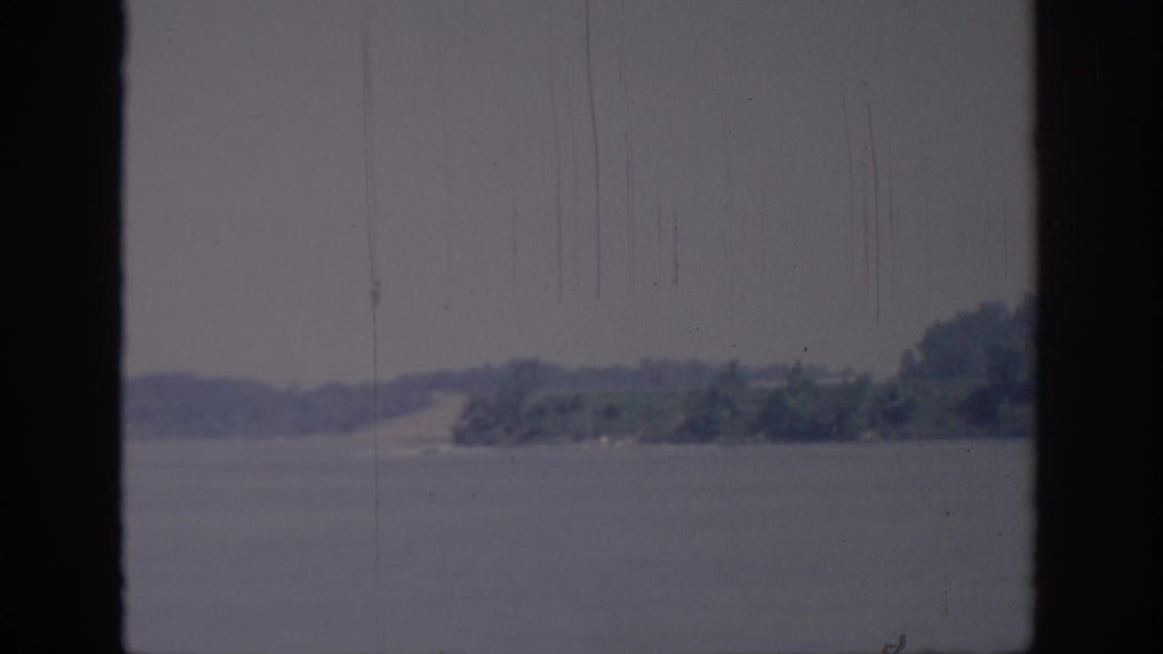 Oklahoma 1967 8mm still with soft-focus water, low shoreline, and trees along the far bank.